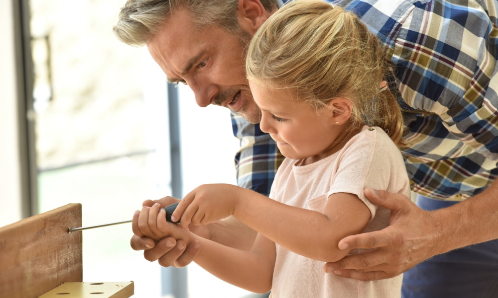 Unmarried Fathers’ Rights Calgary Alberta portrayed by father helping is young daughter learn how to use a screwdriver.